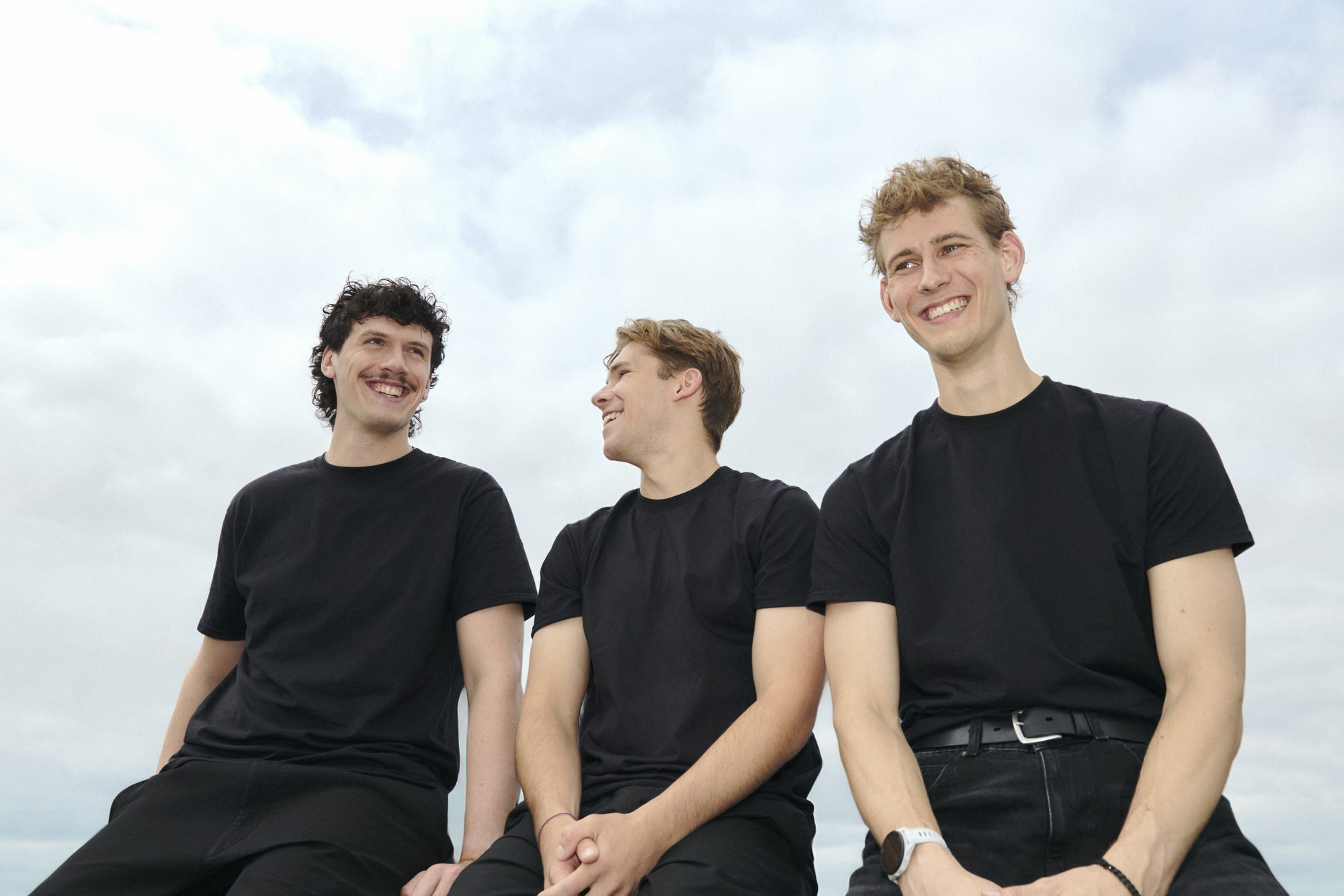 Max, Caesar en Stijn zittend tegen een bewolkte lucht